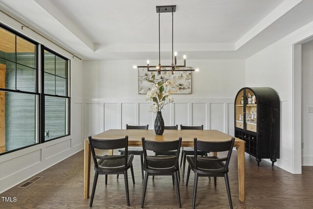 1141 Duke Farm Dr, Wake Forest, NC 27587 - dining space featuring a raised ceiling, a decorative wall, a chandelier, dark wood finished floors, and a wainscoted wall