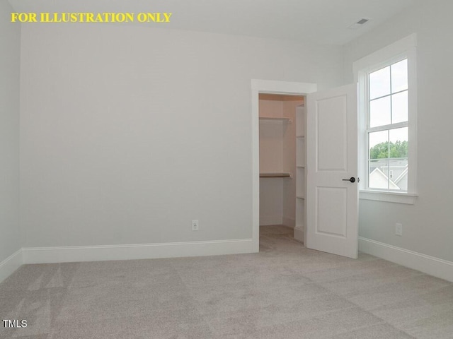 unfurnished bedroom featuring a walk in closet, carpet, and baseboards