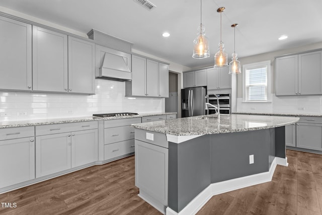 6624 Vestal St, Wake Forest, NC 27587 - kitchen featuring stainless steel appliances, gray cabinetry, custom exhaust hood, decorative backsplash, and an island with sink