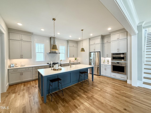 1029 Whitehall Cir, Durham, NC 27713 - kitchen with stainless steel appliances, wall chimney range hood, a sink, a breakfast bar area, and light wood-style flooring
