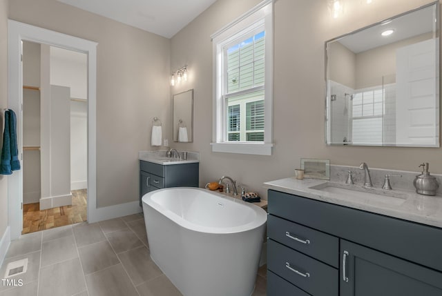 1029 Whitehall Cir, Durham, NC 27713 - full bathroom with tiled shower, two vanities, a soaking tub, baseboards, and tile patterned floors