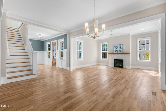 1029 Whitehall Cir, Durham, NC 27713 - unfurnished living room featuring a chandelier, stairs, ornamental molding, light wood-type flooring, and a glass covered fireplace