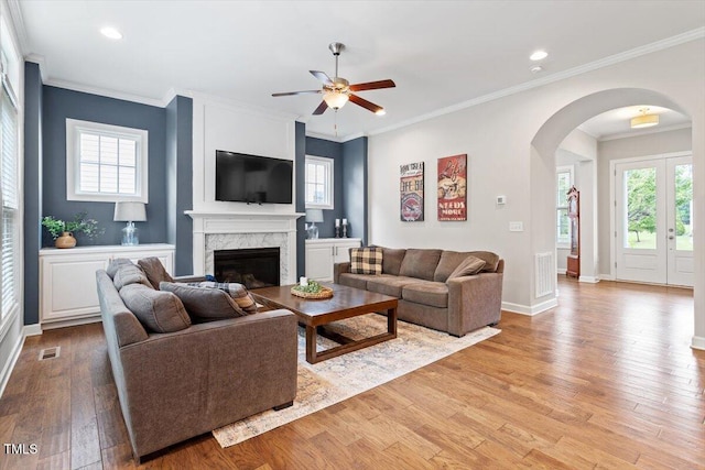 213 Preatonwood Dr, Apex, NC 27539 - living room featuring arched walkways, ceiling fan, a high end fireplace, wood finished floors, and healthy amount of natural light
