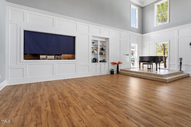 213 Preatonwood Dr, Apex, NC 27539 - living room with a decorative wall, built in shelves, a towering ceiling, wood finished floors, and crown molding