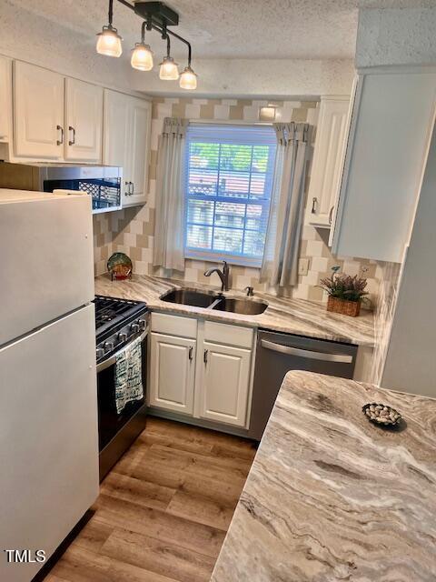 141 Jones Franklin Rd Unit G, Raleigh, NC 27606 - kitchen with stainless steel appliances, a sink, white cabinetry, light countertops, and tasteful backsplash