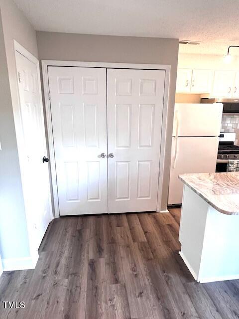 141 Jones Franklin Rd Unit G, Raleigh, NC 27606 - kitchen featuring freestanding refrigerator, gas stove, dark wood-type flooring, white cabinetry, and light stone countertops