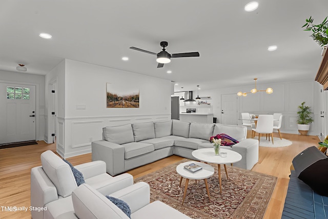 4259 Old Faison Rd, Knightdale, NC 27545 - living room featuring a decorative wall, light wood-type flooring, ceiling fan, wainscoting, and a chandelier