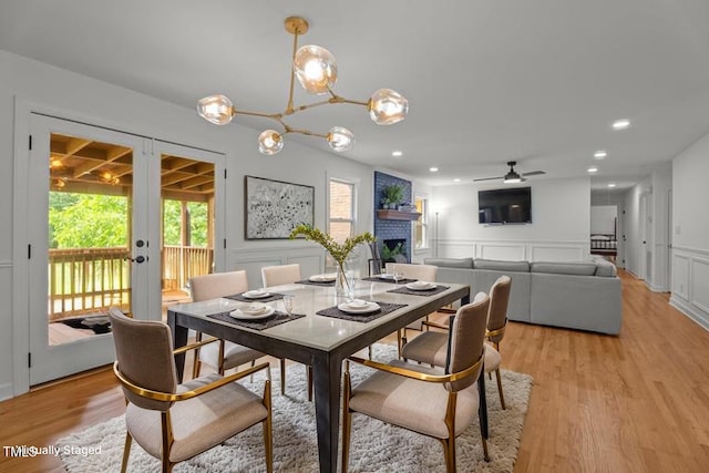 4259 Old Faison Rd, Knightdale, NC 27545 - dining space with french doors, a decorative wall, light wood finished floors, a ceiling fan, and a fireplace