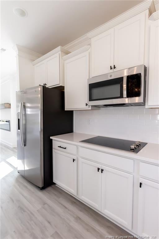 00 John B Carter Rd, Fayetteville, NC 28312 - kitchen featuring appliances with stainless steel finishes, tasteful backsplash, light wood-type flooring, white cabinets, and light countertops