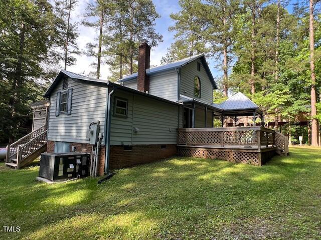 358 Pool Rock Shores Ln, Henderson, NC 27537 - rear view of house with a chimney, central AC unit, a wooden deck, a yard, and stairs