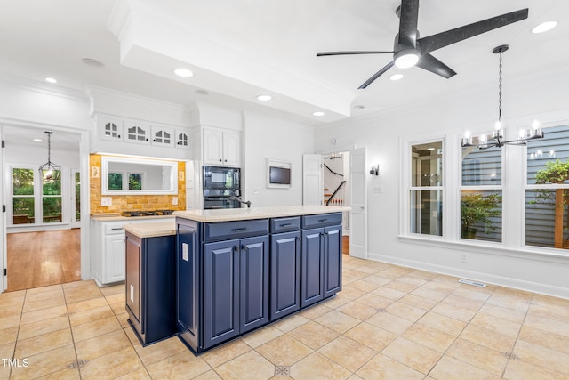 2205 Landings Way, Raleigh, NC 27615 - kitchen with black microwave, blue cabinets, ornamental molding, light countertops, and white cabinetry