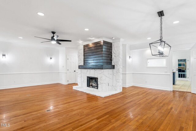 2205 Landings Way, Raleigh, NC 27615 - unfurnished living room featuring crown molding, a stone fireplace, a ceiling fan, light wood-style flooring, and recessed lighting