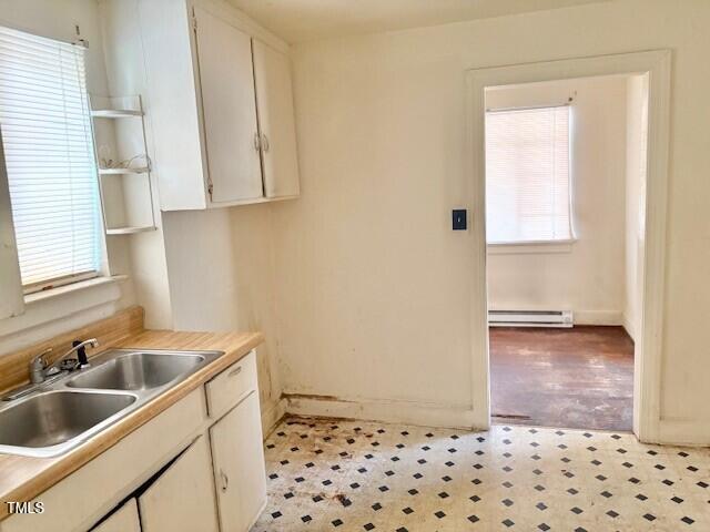 kitchen with a baseboard radiator, healthy amount of natural light, a sink, and light floors