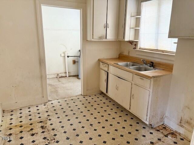 kitchen with a sink, light floors, light countertops, and open shelves