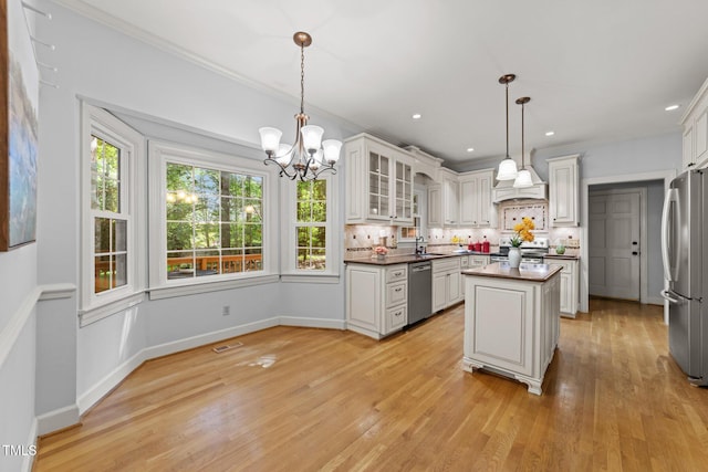 2840 Mattlyn Ct, Raleigh, NC 27613 - kitchen with stainless steel appliances, a chandelier, decorative backsplash, dark countertops, and ornamental molding