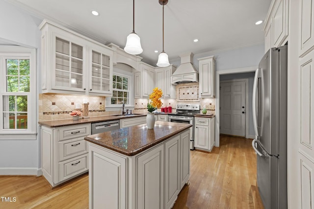 2840 Mattlyn Ct, Raleigh, NC 27613 - kitchen featuring stainless steel appliances, premium range hood, a sink, a kitchen island, and light wood-type flooring