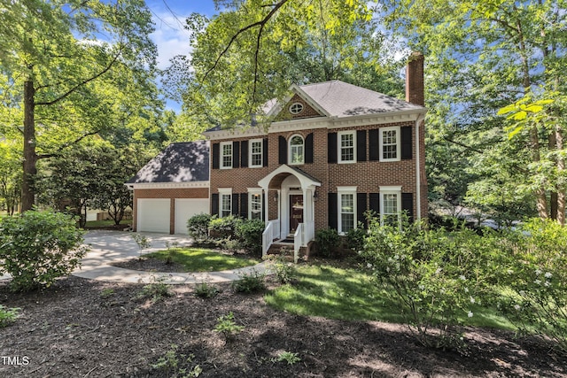 2125 Oakcrest Ct, Raleigh, NC 27612 - colonial home featuring brick siding, a chimney, an attached garage, driveway, and a shingled roof
