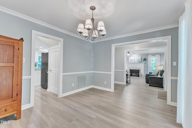 2125 Oakcrest Ct, Raleigh, NC 27612 - unfurnished dining area featuring light wood finished floors, a chandelier, crown molding, baseboards, and a fireplace