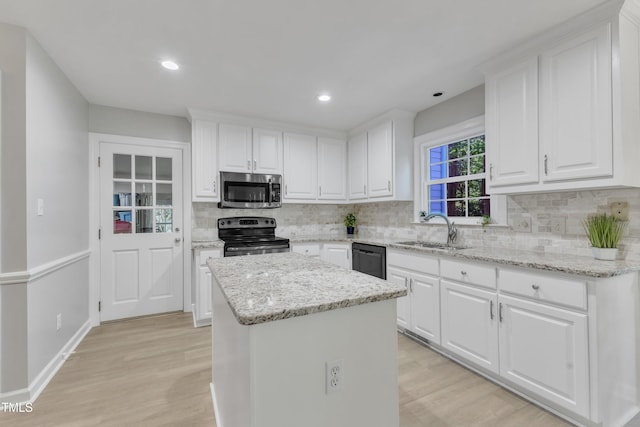 2125 Oakcrest Ct, Raleigh, NC 27612 - kitchen with appliances with stainless steel finishes, a sink, a center island, light wood finished floors, and backsplash