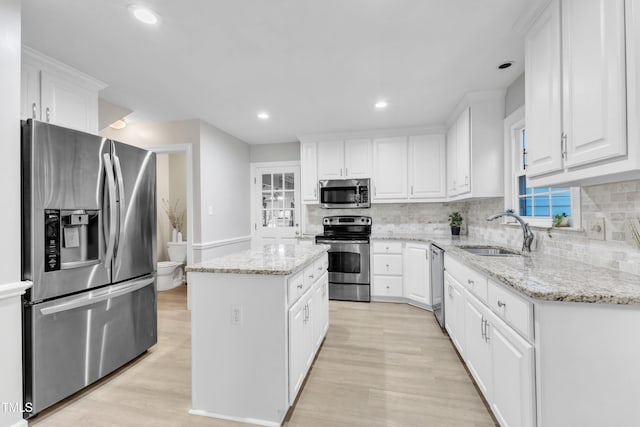 2125 Oakcrest Ct, Raleigh, NC 27612 - kitchen with appliances with stainless steel finishes, a sink, a kitchen island, light wood-style flooring, and recessed lighting