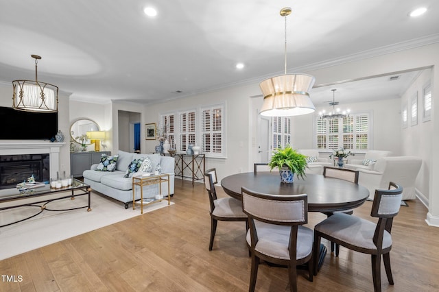 1010 Sandbar Ln, Durham, NC 27703 - dining room featuring wood finished floors, a chandelier, crown molding, recessed lighting, and a glass covered fireplace