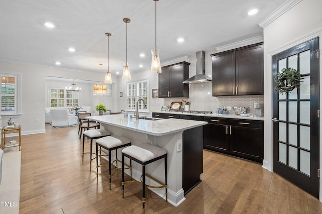 1010 Sandbar Ln, Durham, NC 27703 - kitchen featuring wall chimney exhaust hood, a sink, stainless steel gas cooktop, ornamental molding, and a breakfast bar area
