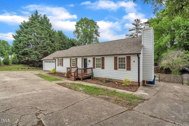 ranch-style home featuring concrete driveway, roof with shingles, a chimney, an attached garage, and fence