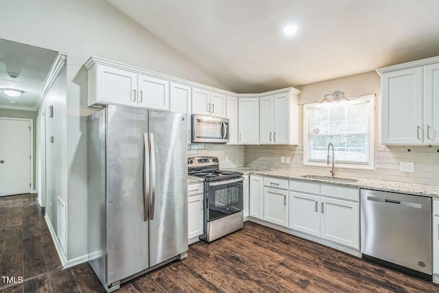 kitchen featuring appliances with stainless steel finishes, a sink, white cabinetry, decorative backsplash, and vaulted ceiling