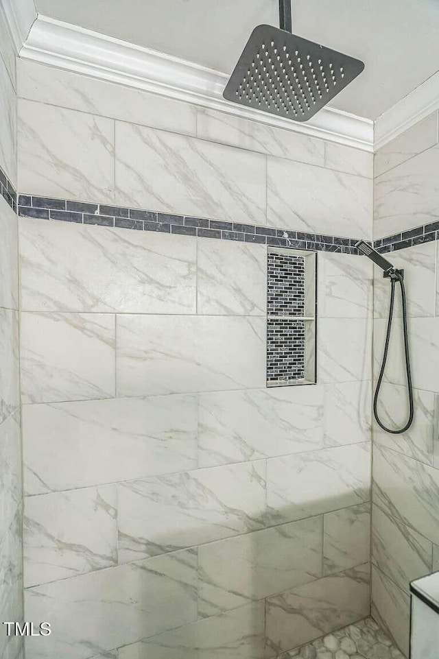 full bathroom featuring a tile shower and ornamental molding