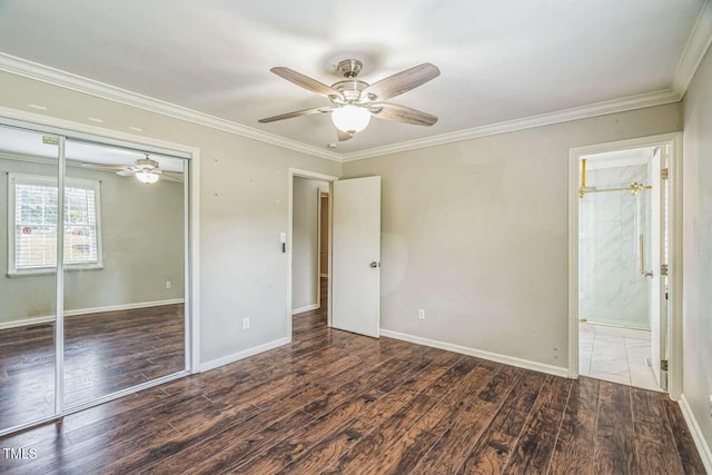 unfurnished bedroom with a closet, wood finished floors, crown molding, baseboards, and ensuite bathroom