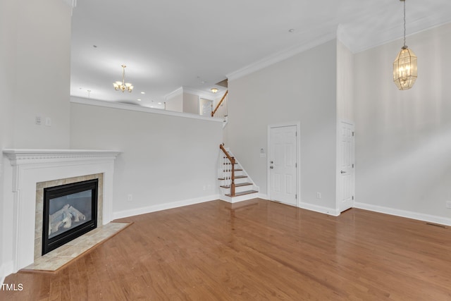 9211 Calabria Dr Unit 104, Raleigh, NC 27617 - unfurnished living room featuring crown molding, a chandelier, wood finished floors, baseboards, and stairs