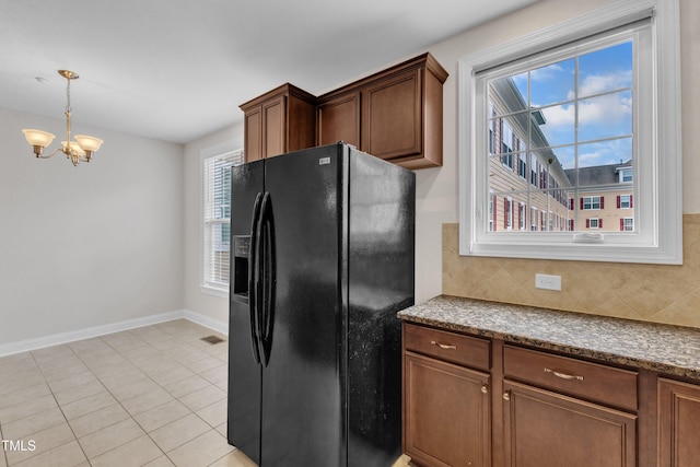 9211 Calabria Dr Unit 104, Raleigh, NC 27617 - kitchen featuring black fridge, a chandelier, baseboards, tasteful backsplash, and light tile patterned floors