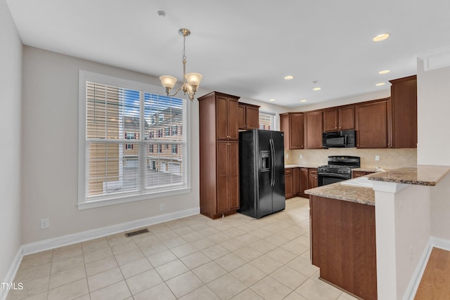 9211 Calabria Dr Unit 104, Raleigh, NC 27617 - kitchen with black appliances, a peninsula, light stone countertops, a chandelier, and baseboards