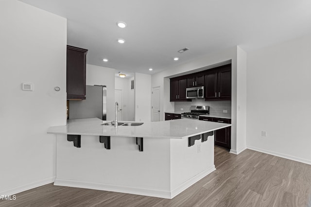 1151 Epiphany Rd, Morrisville, NC 27560 - kitchen featuring appliances with stainless steel finishes, wood finished floors, a kitchen breakfast bar, a peninsula, and tasteful backsplash