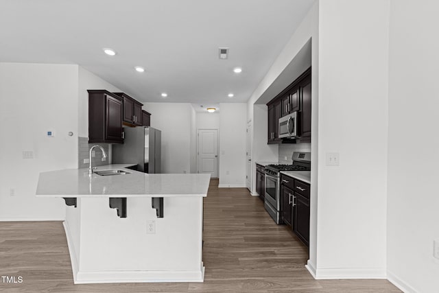 1151 Epiphany Rd, Morrisville, NC 27560 - kitchen with stainless steel appliances, a peninsula, a kitchen bar, light countertops, and backsplash