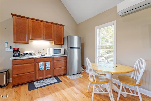 509 Spruce Meadows Ln, Willow Springs, NC 27592 - kitchen with white microwave, freestanding refrigerator, an AC wall unit, vaulted ceiling, and light wood finished floors