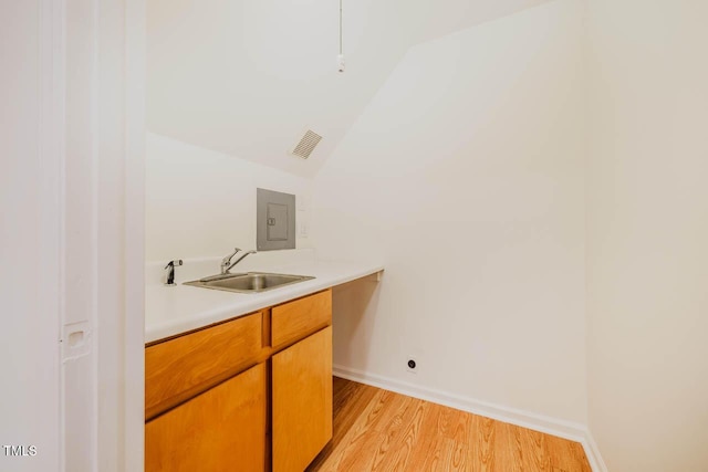 106 Redbud, Pittsboro, NC 27312 - bar area featuring a sink, light wood-style flooring, baseboards, lofted ceiling, and electric panel
