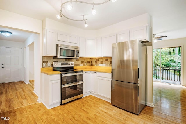 106 Redbud, Pittsboro, NC 27312 - kitchen with stainless steel appliances, light wood-style flooring, white cabinets, and tasteful backsplash