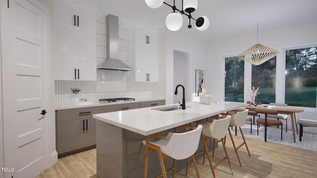 1806 Pershing Rd, Raleigh, NC 27608 - kitchen with a sink, wall chimney exhaust hood, light wood-style flooring, modern cabinets, and tasteful backsplash