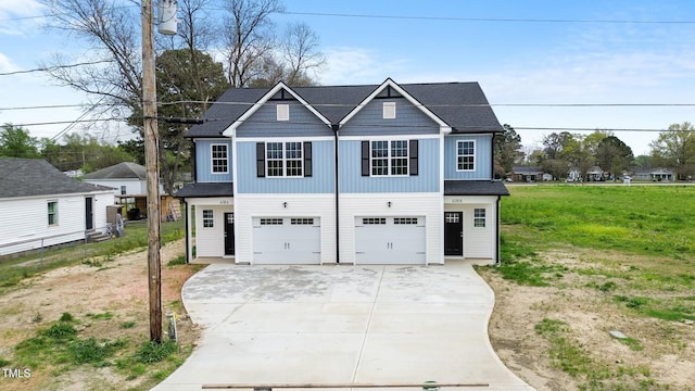 view of front of home featuring an attached garage, driveway, board and batten siding, and a front yard