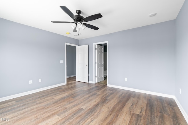 unfurnished bedroom featuring baseboards, wood finished floors, ceiling fan, and a spacious closet