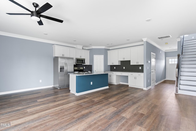 kitchen featuring stainless steel appliances, crown molding, a center island with sink, white cabinets, and baseboards