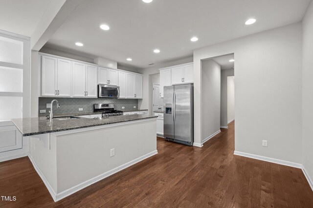 256 Rubrum Dr, Hillsborough, NC 27278 - kitchen with stainless steel appliances, dark stone countertops, a peninsula, backsplash, and white cabinets