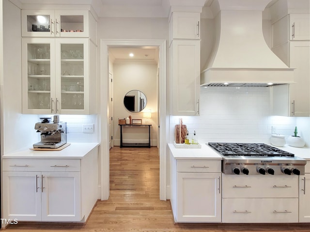 3160 Mantle Ridge Dr, Apex, NC 27502 - kitchen with wall chimney exhaust hood, stainless steel gas stovetop, light wood finished floors, white cabinets, and backsplash