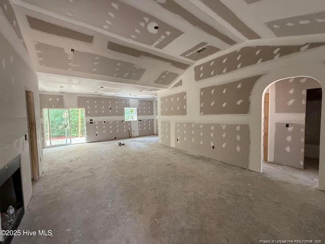 unfurnished living room with arched walkways and vaulted ceiling