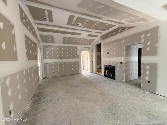 unfurnished living room with arched walkways, a fireplace, and vaulted ceiling