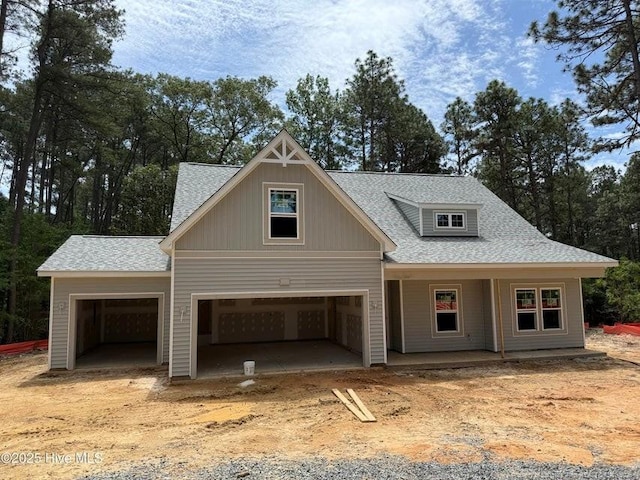 view of front of house with an attached garage, roof with shingles, covered porch, and driveway