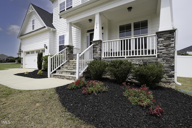 property entrance with a porch, stone siding, driveway, and a shingled roof