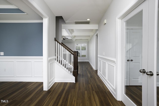 hallway featuring a decorative wall, dark wood-style flooring, coffered ceiling, beam ceiling, and stairway