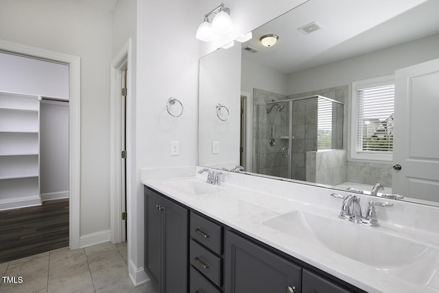 bathroom featuring a stall shower, double vanity, and baseboards